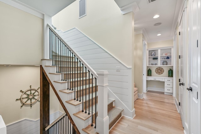 stairs featuring crown molding, hardwood / wood-style floors, and built in desk