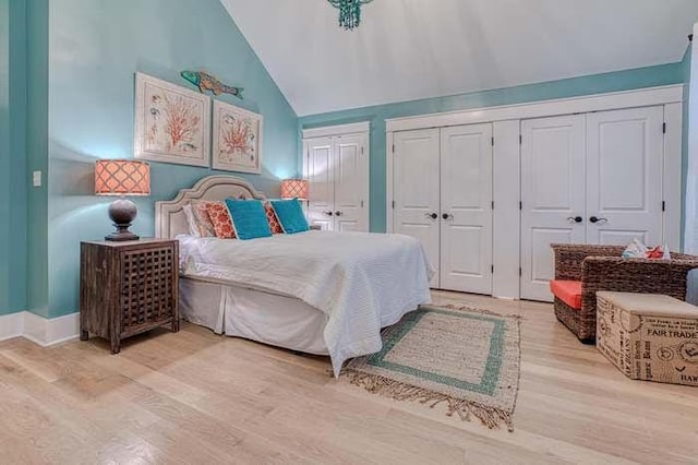 bedroom with light hardwood / wood-style floors, vaulted ceiling, and multiple closets