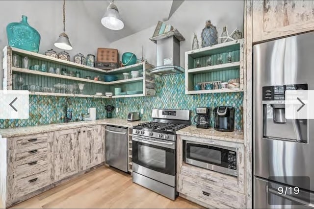 kitchen with light stone countertops, appliances with stainless steel finishes, sink, and wall chimney range hood