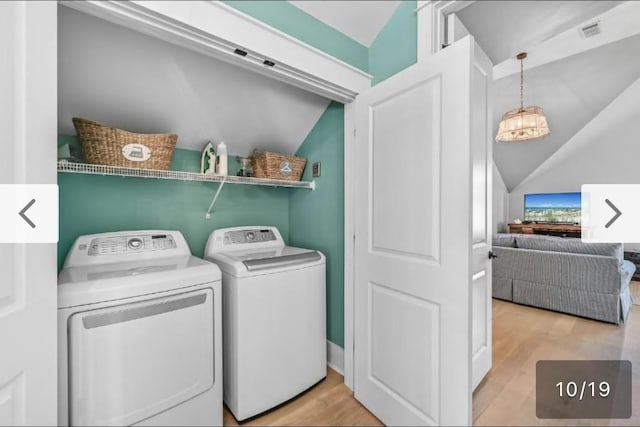 laundry room with a notable chandelier, light hardwood / wood-style floors, and washing machine and dryer