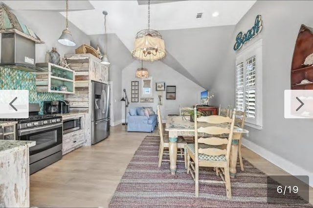 dining space featuring a chandelier, lofted ceiling, and light wood-type flooring