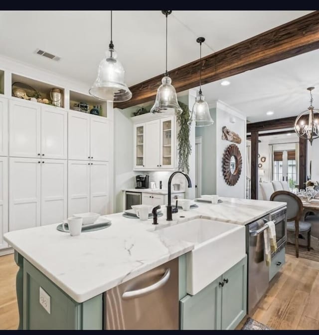 kitchen featuring beam ceiling, white cabinetry, a kitchen island with sink, and pendant lighting