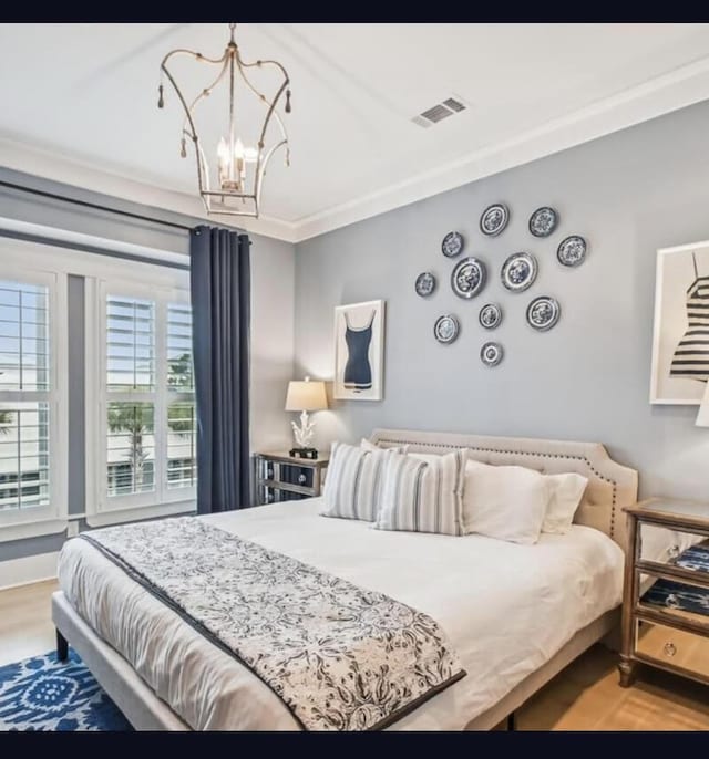 bedroom with a notable chandelier, wood-type flooring, and ornamental molding