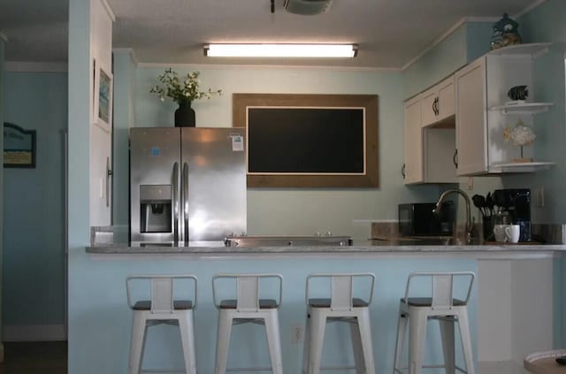 kitchen with a kitchen breakfast bar, kitchen peninsula, stainless steel fridge with ice dispenser, ornamental molding, and white cabinetry