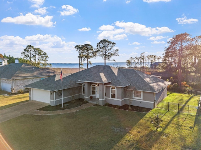 ranch-style home featuring a garage, a front yard, and a water view