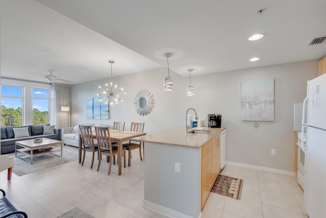 kitchen with light stone countertops, sink, hanging light fixtures, and ceiling fan with notable chandelier