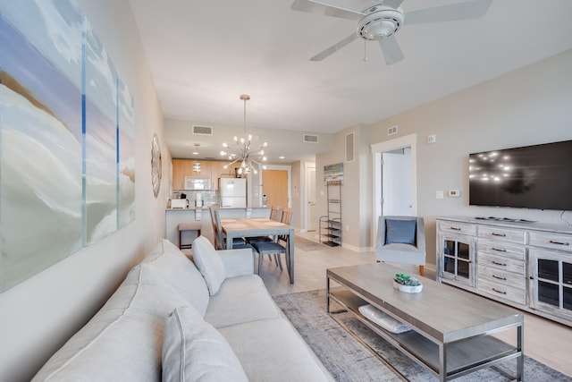 living room with light hardwood / wood-style floors and ceiling fan with notable chandelier