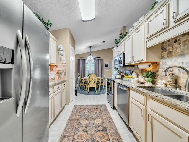 kitchen featuring sink, decorative light fixtures, lofted ceiling, decorative backsplash, and appliances with stainless steel finishes