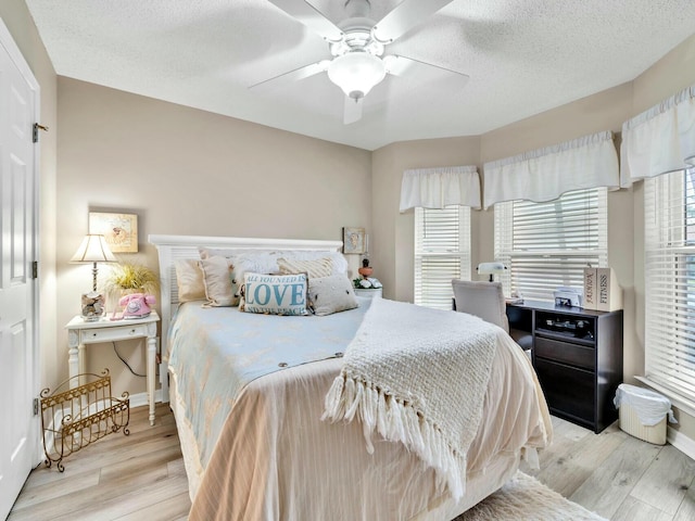 bedroom featuring ceiling fan, light hardwood / wood-style floors, and a textured ceiling