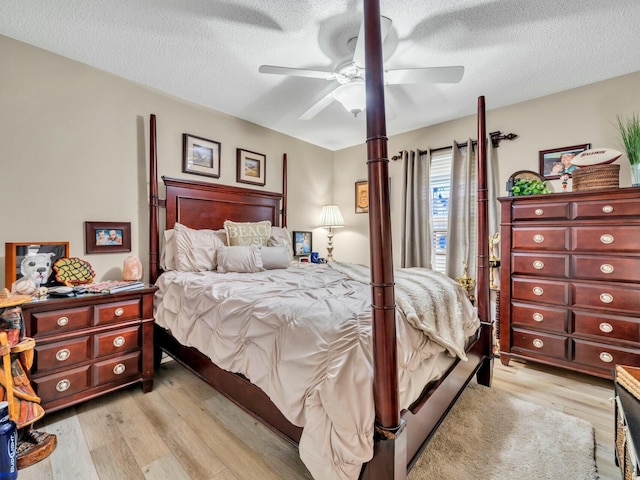 bedroom with a textured ceiling, light hardwood / wood-style flooring, and ceiling fan