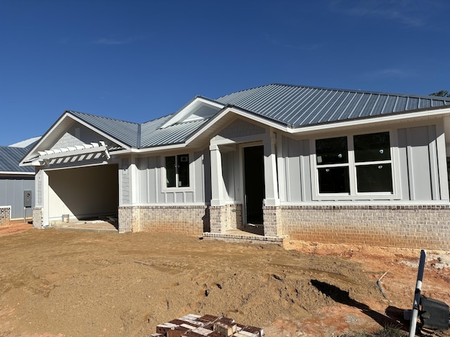 view of front of house featuring metal roof, a garage, board and batten siding, and brick siding