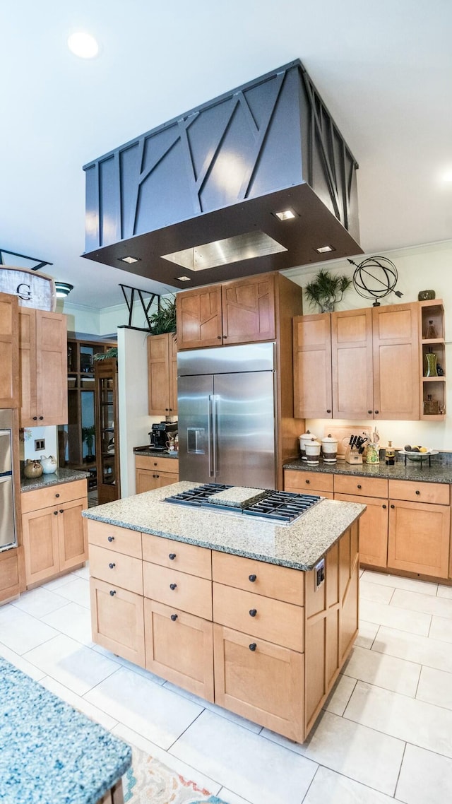 kitchen with light stone countertops, a center island, stainless steel appliances, and light tile patterned flooring