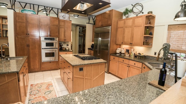 kitchen with light stone countertops, appliances with stainless steel finishes, a center island, and sink