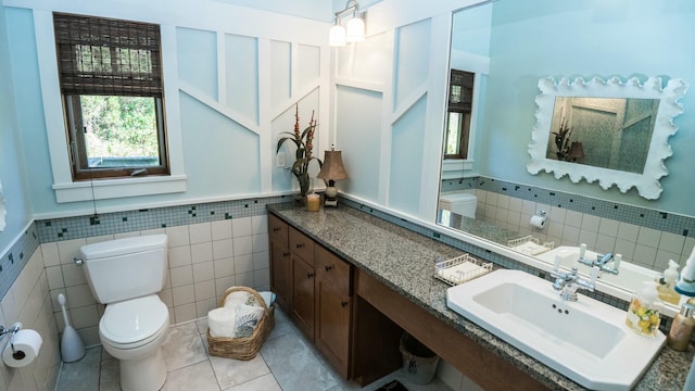 bathroom featuring tile patterned flooring, vanity, toilet, and tile walls