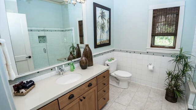 bathroom featuring tile patterned flooring, toilet, vanity, a shower with shower door, and tile walls