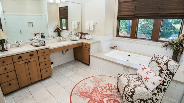 bathroom featuring tile patterned flooring, tiled tub, and sink