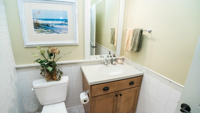 bathroom featuring vanity, tile walls, and toilet