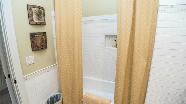 bathroom with tile walls and shower / tub combo with curtain