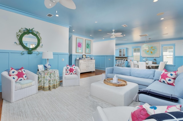 living room with hardwood / wood-style flooring, ceiling fan, and crown molding