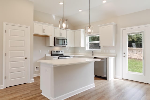 kitchen featuring white cabinetry, a center island, stainless steel appliances, and hanging light fixtures