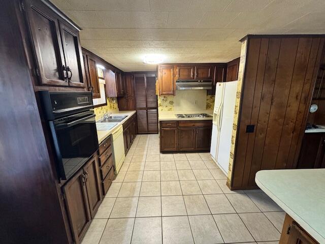 kitchen featuring backsplash, stainless steel gas cooktop, light tile patterned floors, black oven, and white fridge with ice dispenser