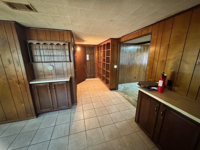 interior space with light tile patterned floors and wooden walls