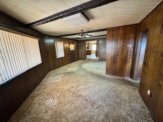 corridor featuring carpet flooring, wood walls, and beam ceiling