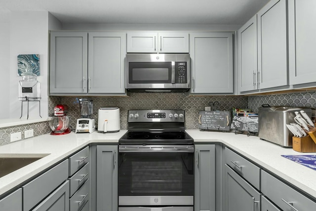 kitchen with decorative backsplash, stainless steel appliances, gray cabinetry, and sink