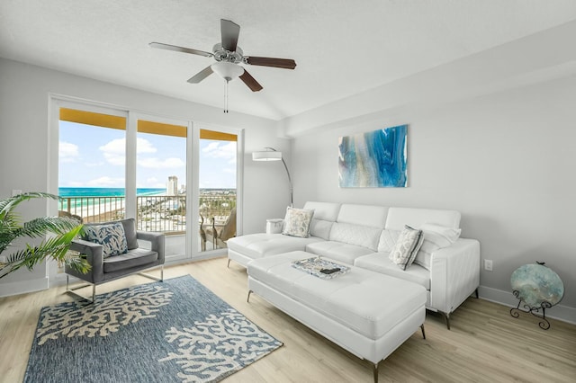 living room featuring ceiling fan, a water view, and light wood-type flooring