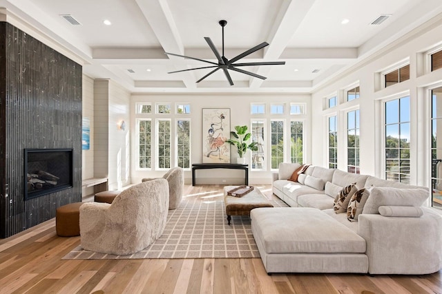 living room with a fireplace, light hardwood / wood-style flooring, a wealth of natural light, and coffered ceiling