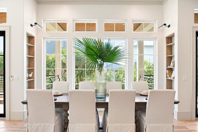 dining space with built in shelves, light wood-type flooring, and a healthy amount of sunlight