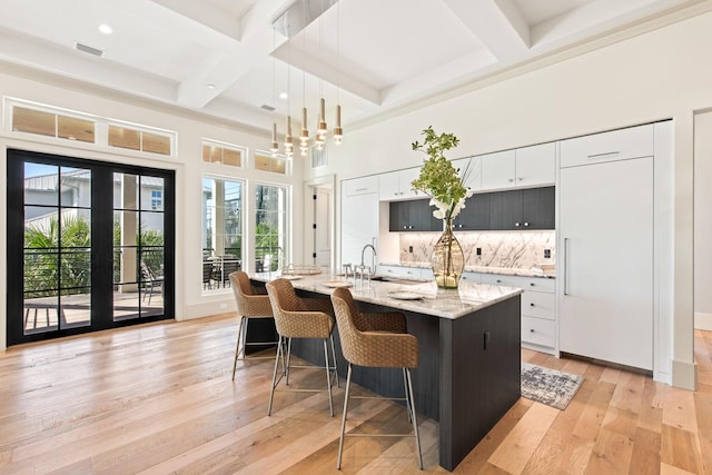 kitchen with a kitchen island with sink, plenty of natural light, white cabinets, and decorative light fixtures