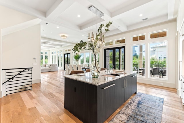 kitchen featuring a large island, sink, french doors, hanging light fixtures, and coffered ceiling