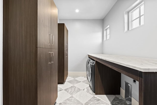 kitchen with washer and clothes dryer, light stone counters, and dark brown cabinetry