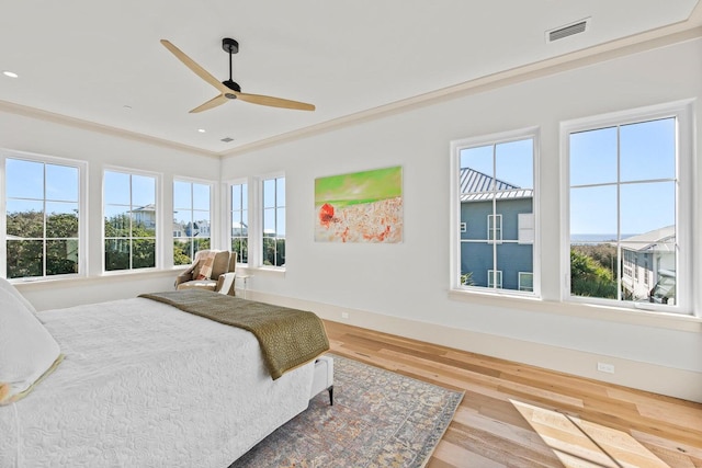 bedroom with multiple windows, ceiling fan, hardwood / wood-style floors, and ornamental molding