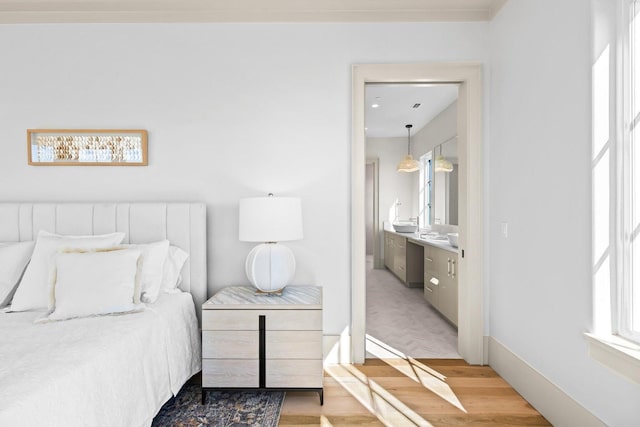 bedroom with connected bathroom and light wood-type flooring