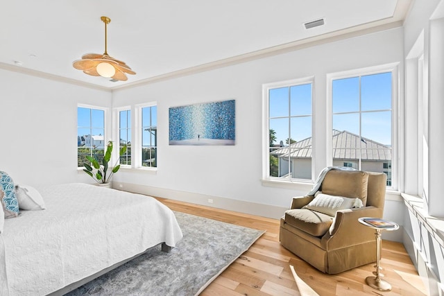 bedroom with multiple windows, ceiling fan, crown molding, and light hardwood / wood-style floors