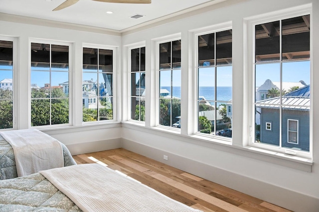 sunroom featuring ceiling fan and a water view