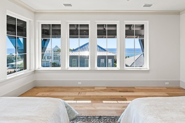 bedroom with hardwood / wood-style floors, a water view, and crown molding