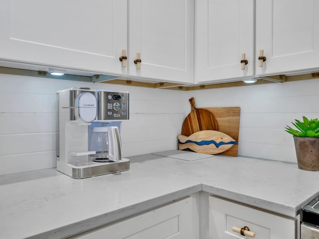 interior details with range with electric stovetop, white cabinetry, and light stone counters