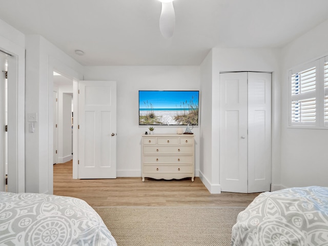 bedroom featuring ceiling fan, light hardwood / wood-style flooring, and a closet