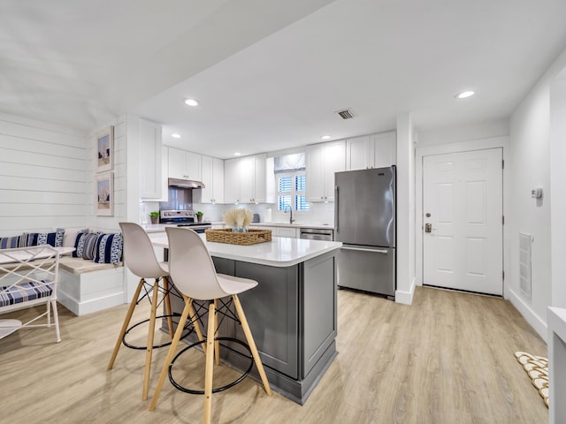 kitchen featuring stainless steel appliances, white cabinetry, light hardwood / wood-style flooring, a breakfast bar area, and breakfast area