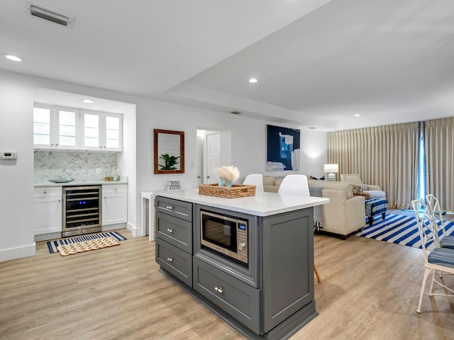 kitchen featuring wine cooler, gray cabinetry, light hardwood / wood-style floors, white cabinetry, and tasteful backsplash