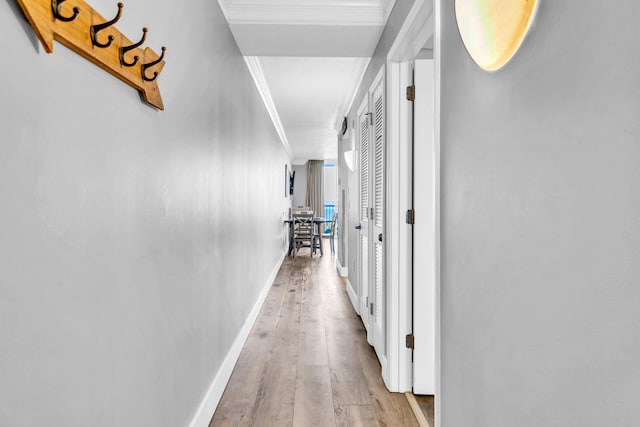 corridor with light hardwood / wood-style flooring and crown molding