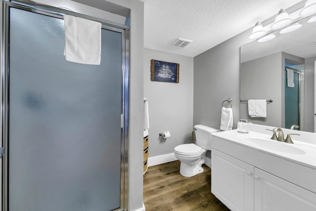 bathroom with a textured ceiling, vanity, toilet, walk in shower, and hardwood / wood-style flooring