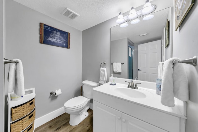 bathroom with a textured ceiling, toilet, hardwood / wood-style floors, and vanity