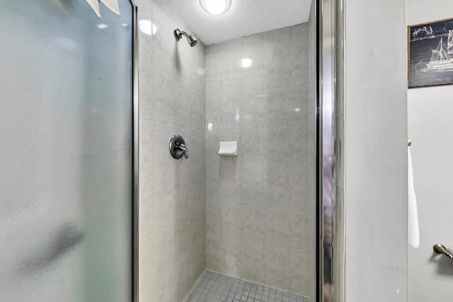 bathroom with a shower with shower door and a textured ceiling