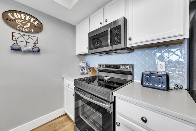 kitchen featuring tasteful backsplash, white cabinets, stainless steel appliances, and light hardwood / wood-style floors