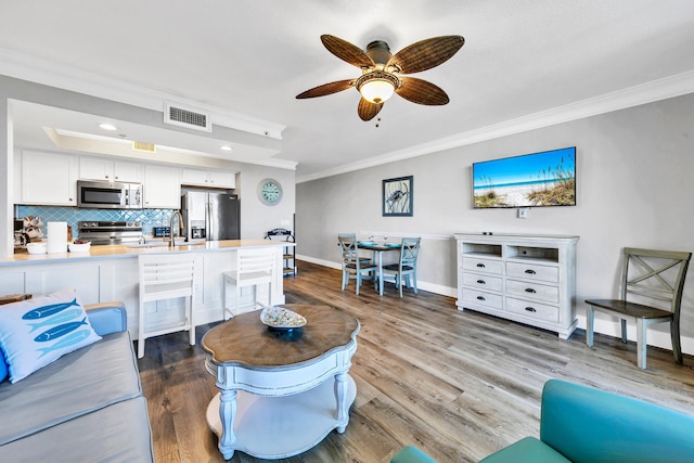 living room with ceiling fan, sink, crown molding, and hardwood / wood-style floors