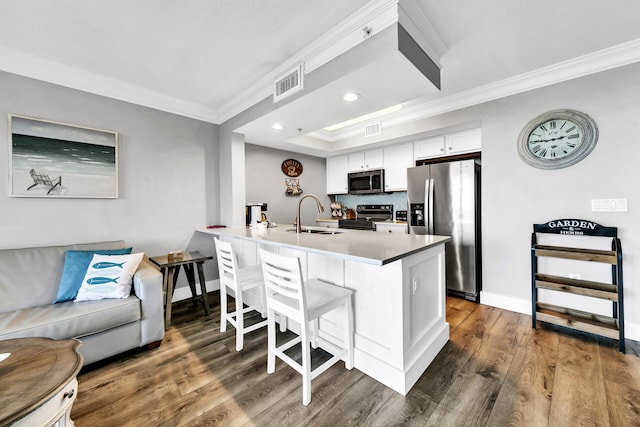 kitchen featuring kitchen peninsula, a kitchen bar, sink, white cabinetry, and stainless steel appliances